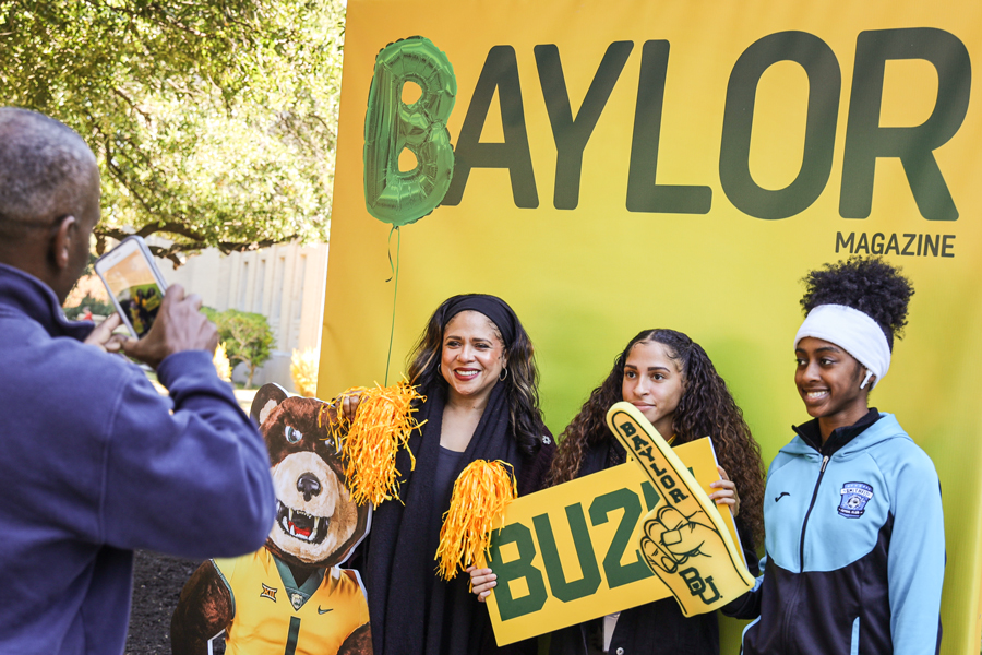 Family in front of Baylor themed backdrop taking photo