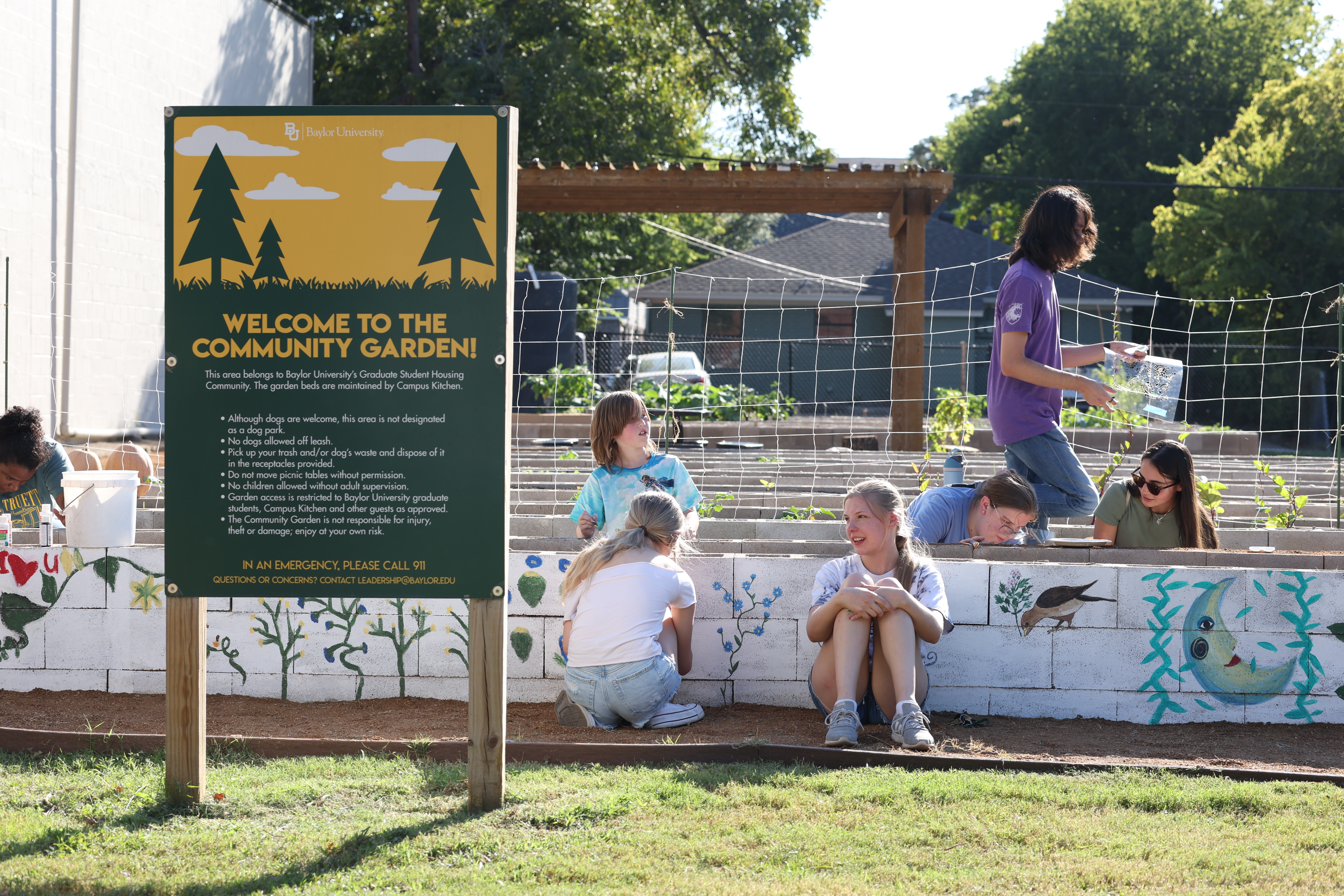 Students and community members surround a raised garden bed at Baylor's Community Garden.