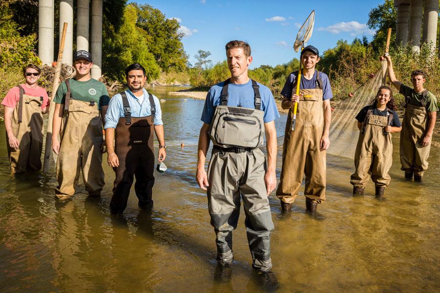 Ryan McManamay, Ph.D., leads students from his Field Techniques for Environmental Science course in hands-on training, demonstrating proper methods for collecting high-quality water samples.