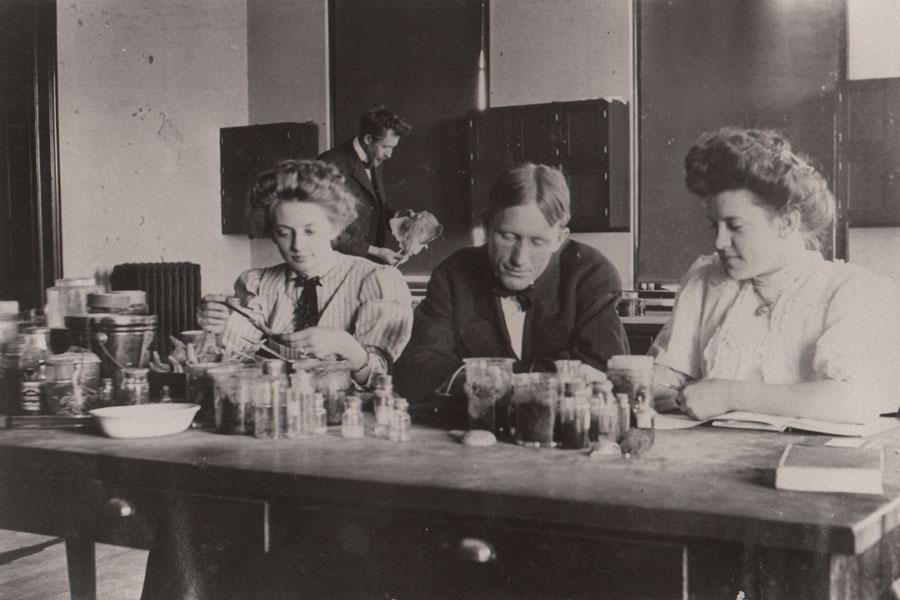Historic photo of students conducting experiments at a science classroom table.