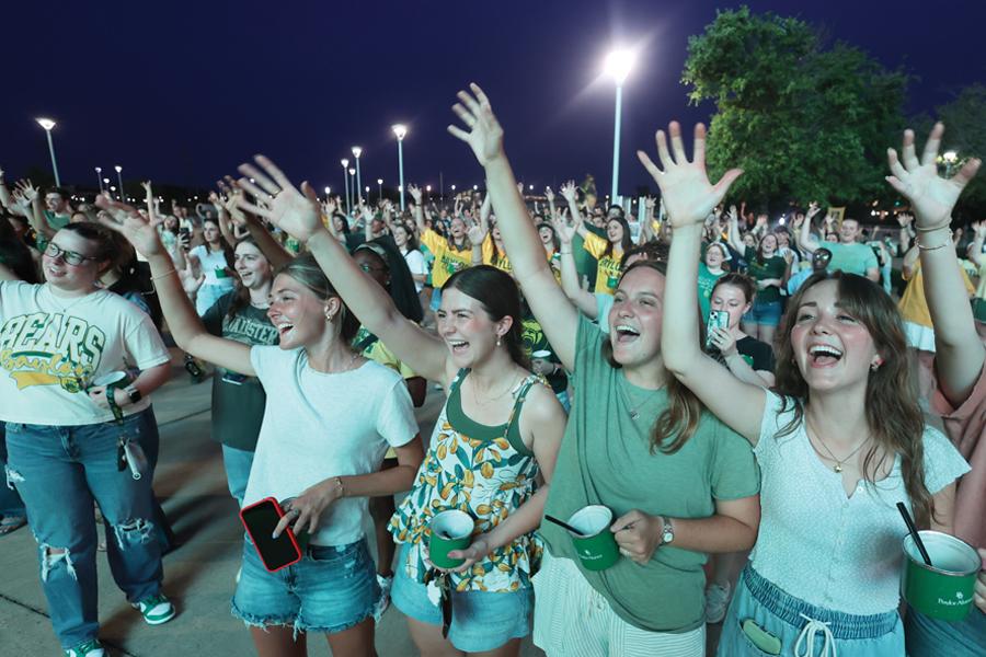 Graduating seniors cheer with raised arms at the evening Line to Legacy celebration outside McLane Stadium.