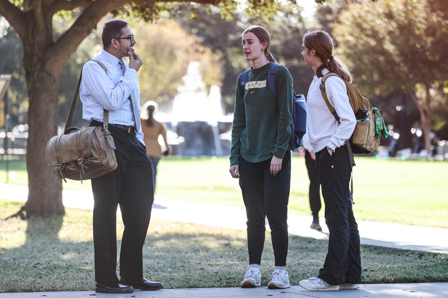  Rishi Sriram, Ph.D. talking with a couple of students on campus