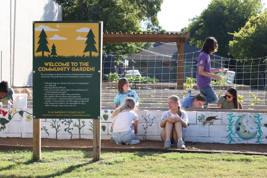 Students and community members surrounding some raised garden beds at Baylor's Community Garden. 